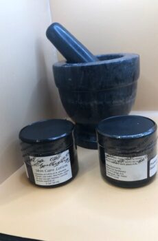 Two amber glass jars of natural lotion sitting in front of a mortar and pestle.