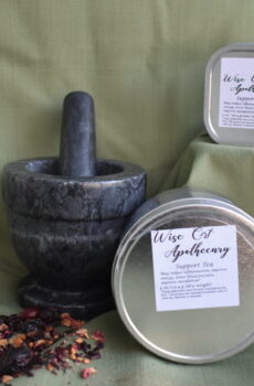 A mortar and pestle, a square tin containing rosehip hibiscus tea blend and a round tin containing rosehip hibiscus tea blend.